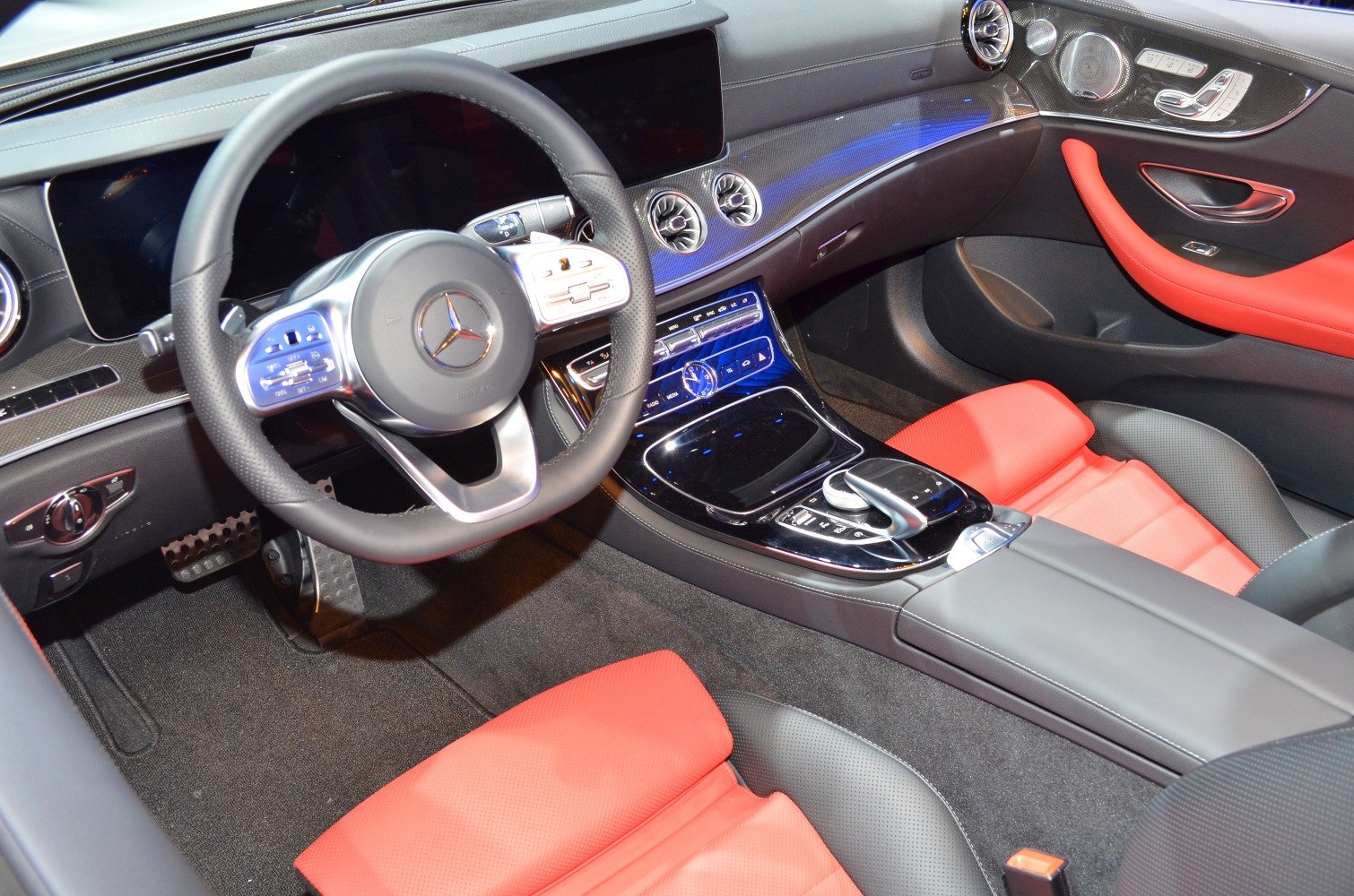 Luxury interior with steering wheel, digital displays, and red leather seating