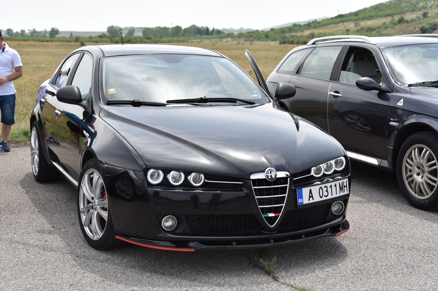 Triple headlights and V-shaped grille on black sedan front view