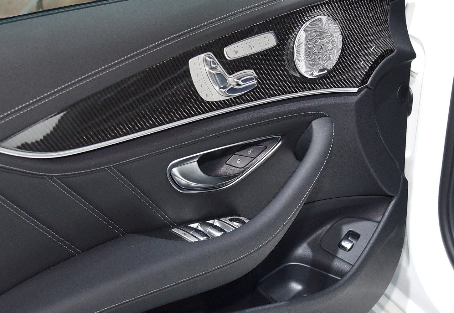 Luxury car door panel with seat controls and premium audio speaker