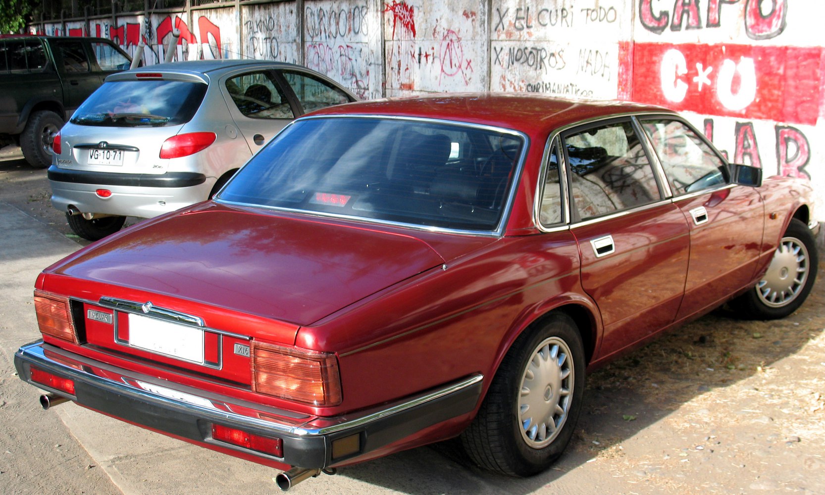Red luxury sedan rear side with chrome trim and dual exhaust.
