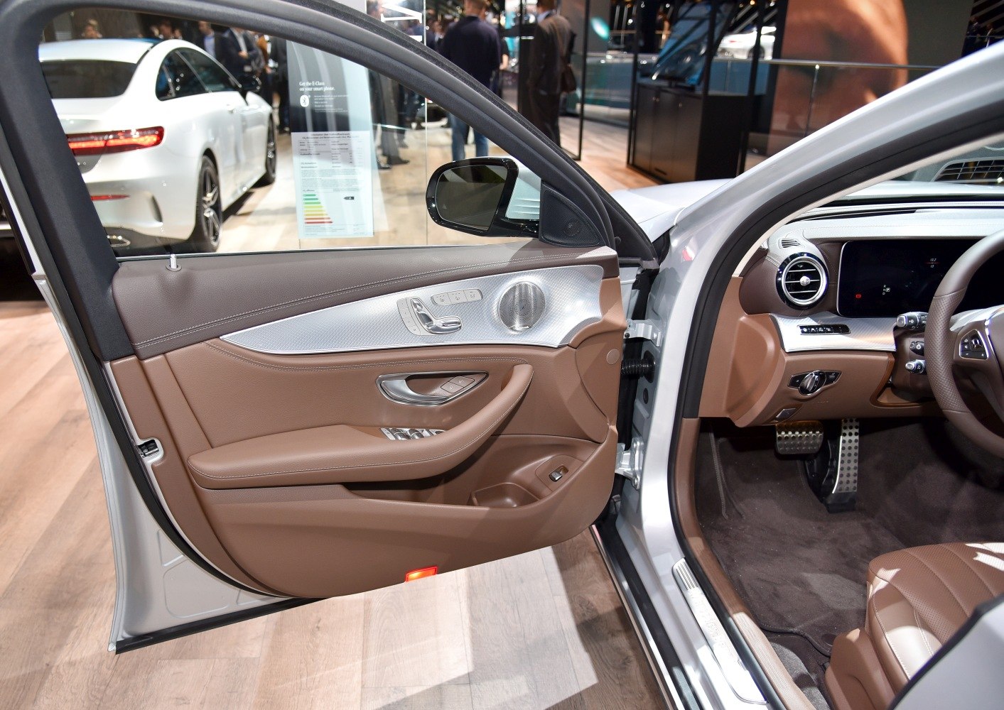 Brown leather car door panel with metallic accents and control buttons