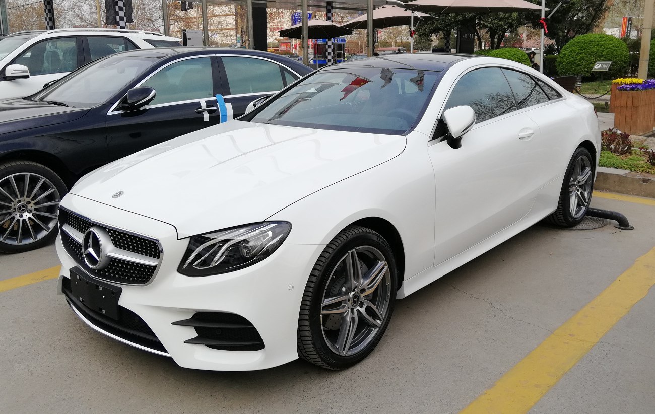 White coupe with prominent front grille and sporty alloy wheels