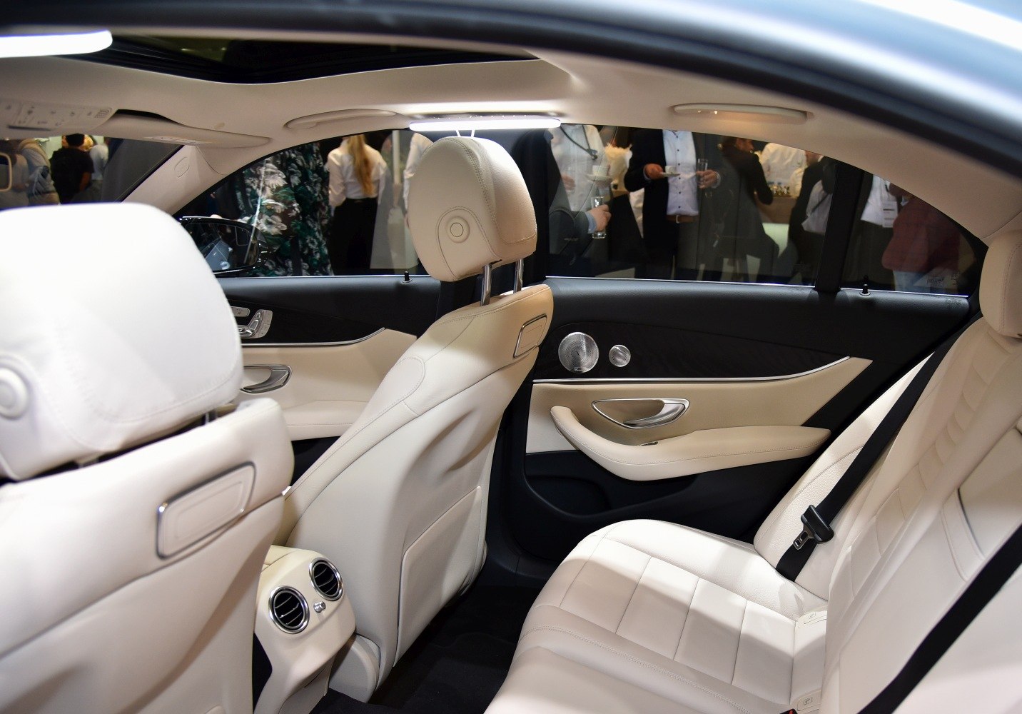 Rear passenger interior with beige leather upholstery and ambient lighting