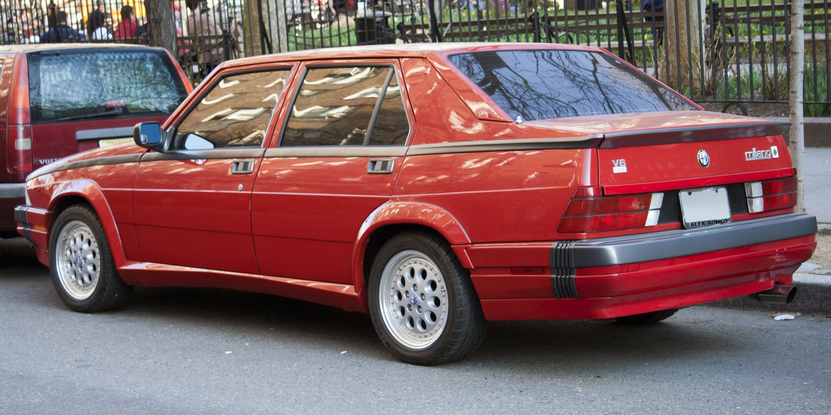 Red classic sedan rear side with alloy wheels and rear spoiler