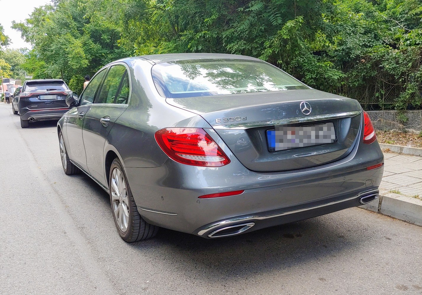 Rear view of luxury sedan with dual chrome exhausts and distinctive tail lights