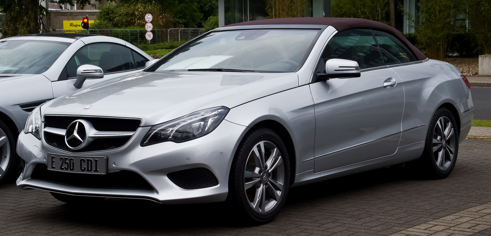 Silver convertible coupe with fabric soft top and sharp headlights