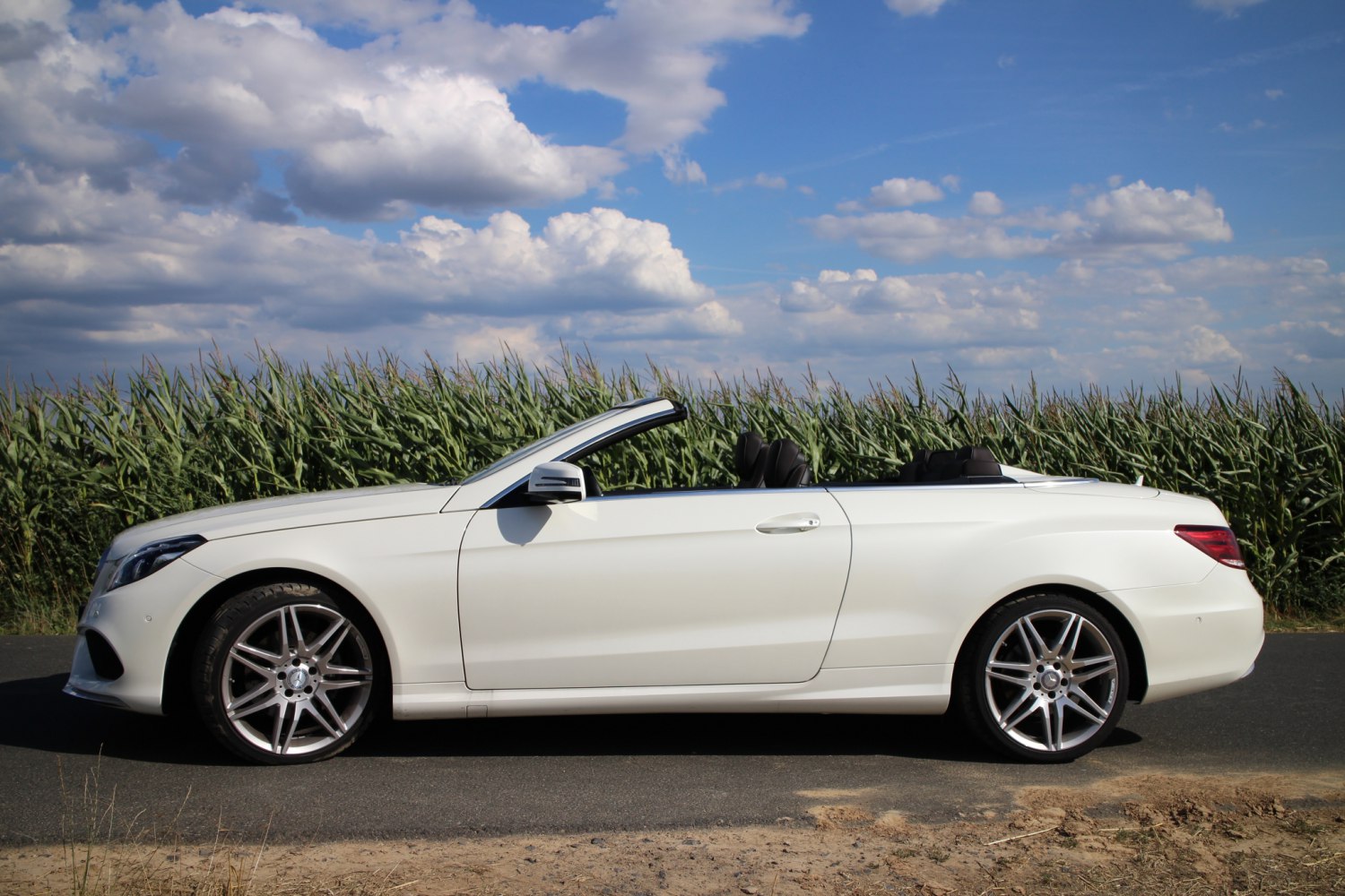Side view of a white convertible with alloy wheels and roof down