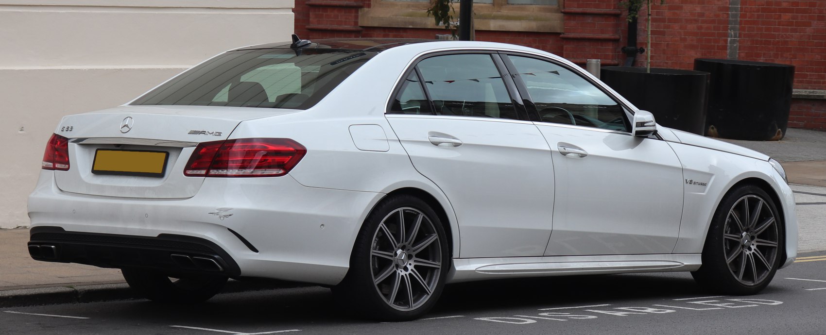 Rear side view of a white luxury sedan with AMG and V8 biturbo badges
