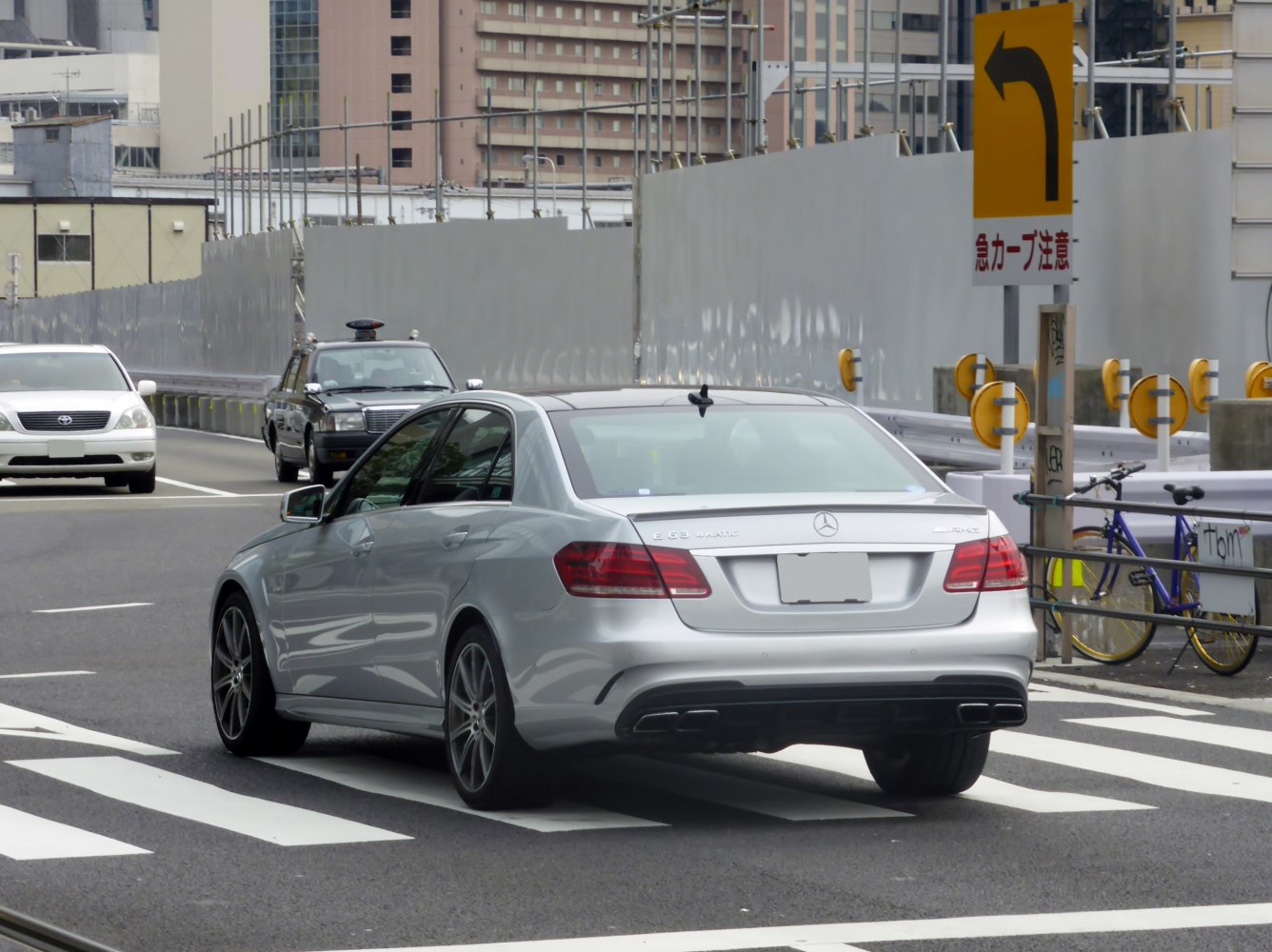 Silver luxury sedan rear with AMG quad exhausts on city street