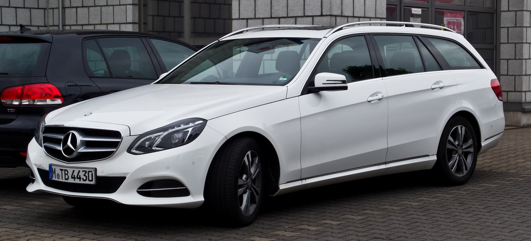 White station wagon with roof rails and alloy wheels.