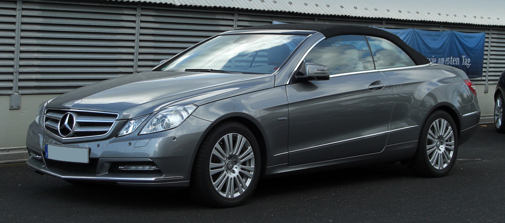 Silver convertible with black soft top and alloy wheels side view