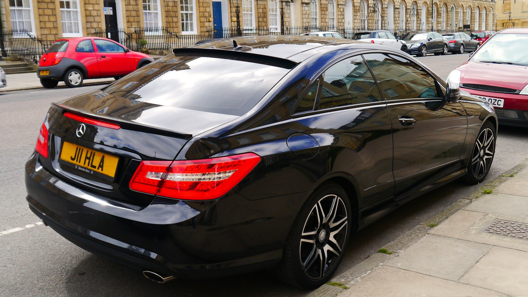 Rear side view of a sleek coupe with taillights and sporty alloy wheels