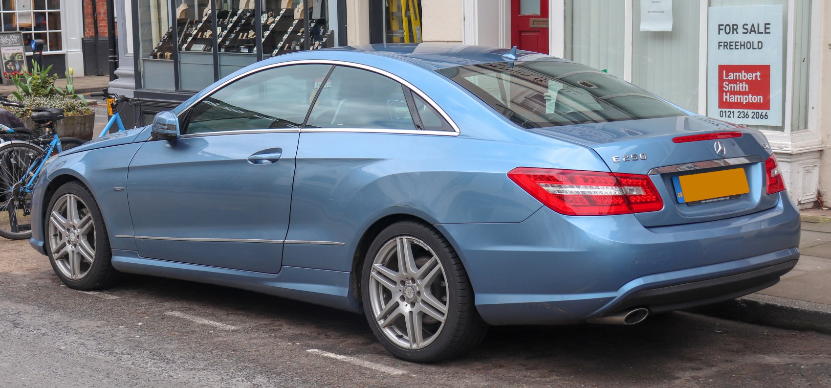 Rear side view of a blue two-door coupe with alloy wheels and distinct tail lights
