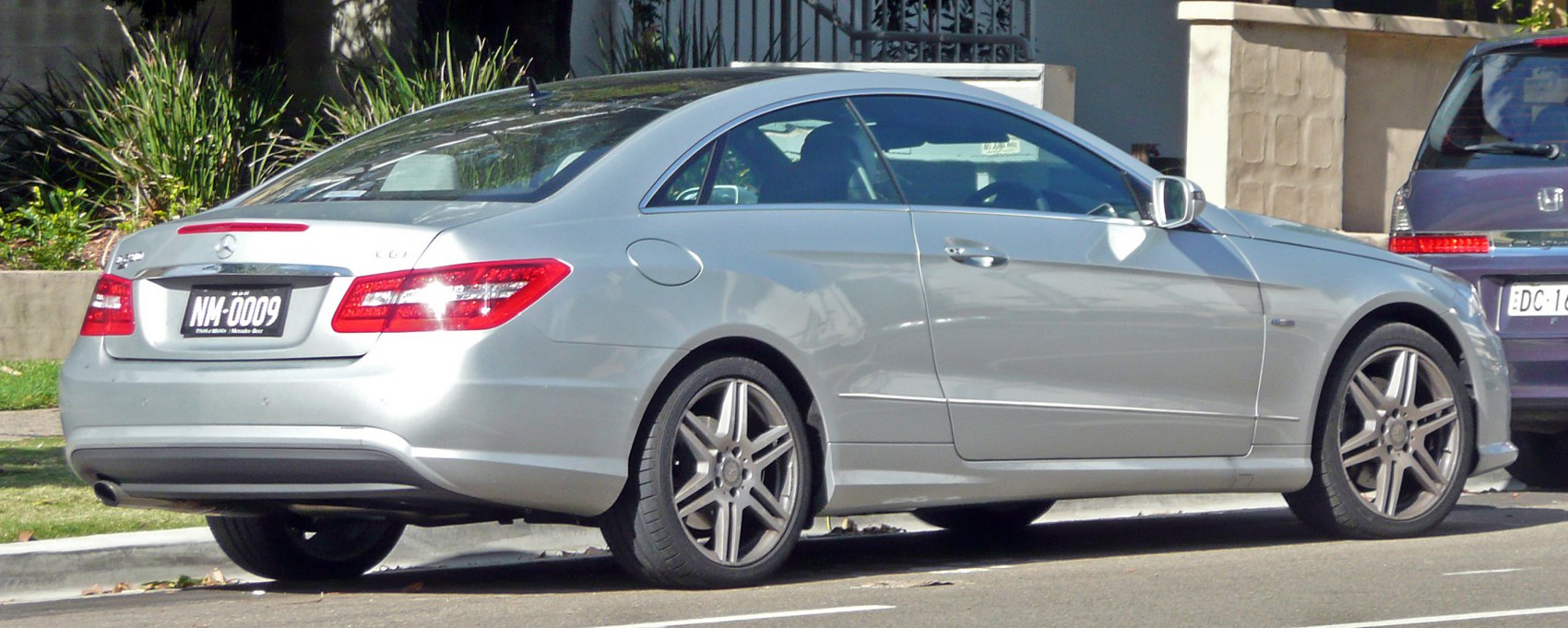 Silver two-door coupe with rear and side view, alloy wheels, and sleek design