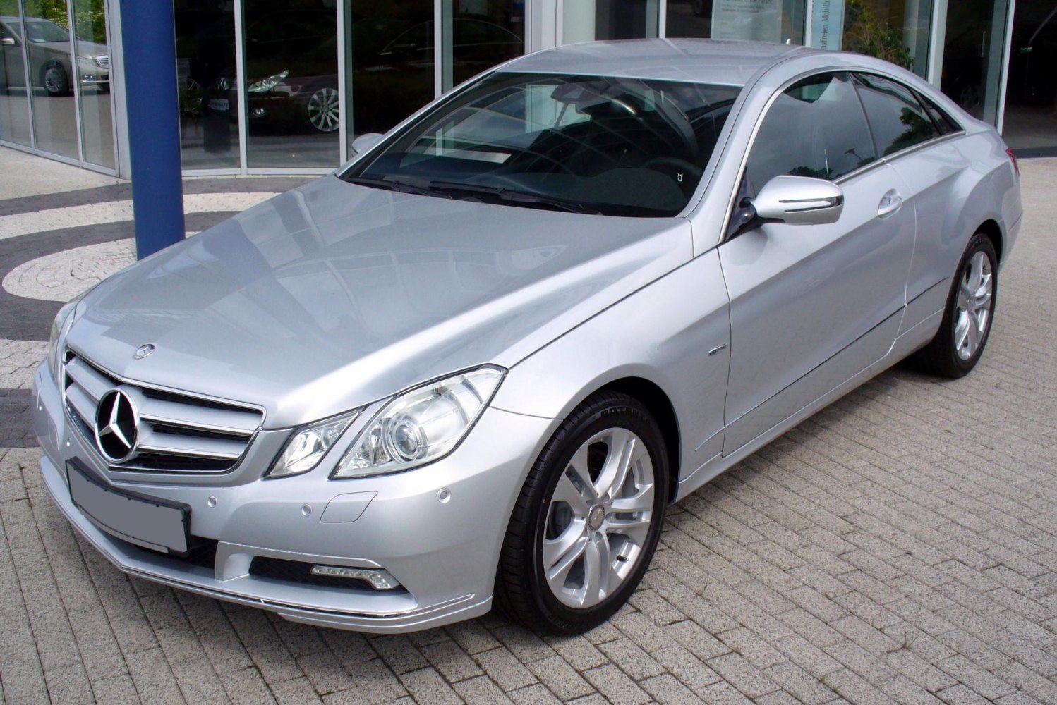 Silver luxury coupe with sleek headlights and alloy wheels front-side view