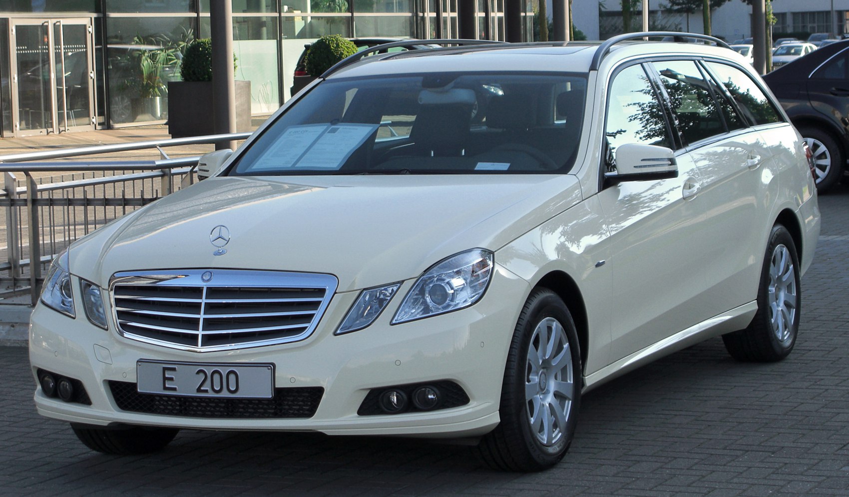 Front and side view of a white wagon with roof rails and detailed headlights
