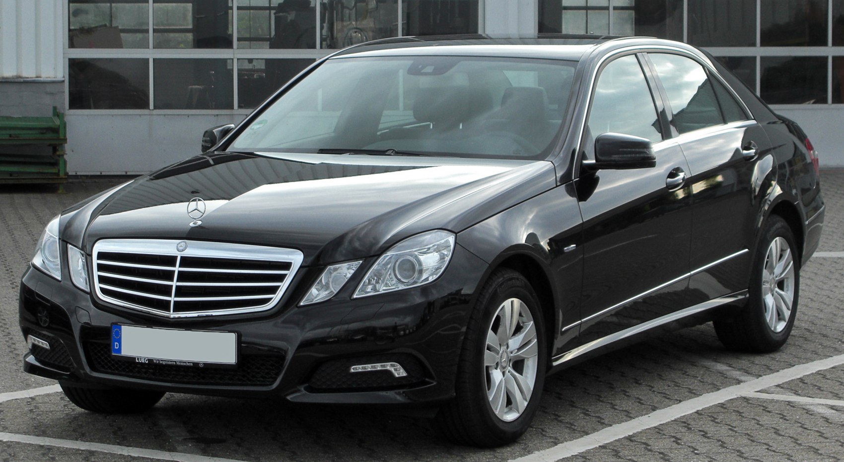 Front three-quarter view of black sedan with prominent grille and headlights.