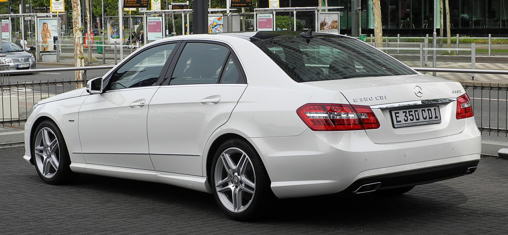Rear and side profile of white luxury sedan with alloy wheels
