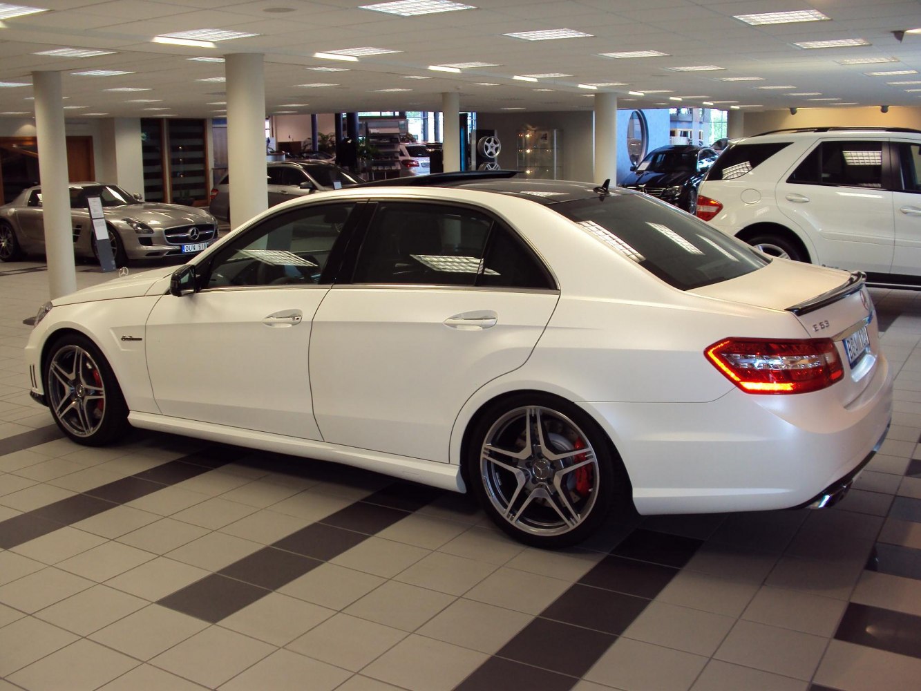 White sedan with AMG rims and rear spoiler in showroom
