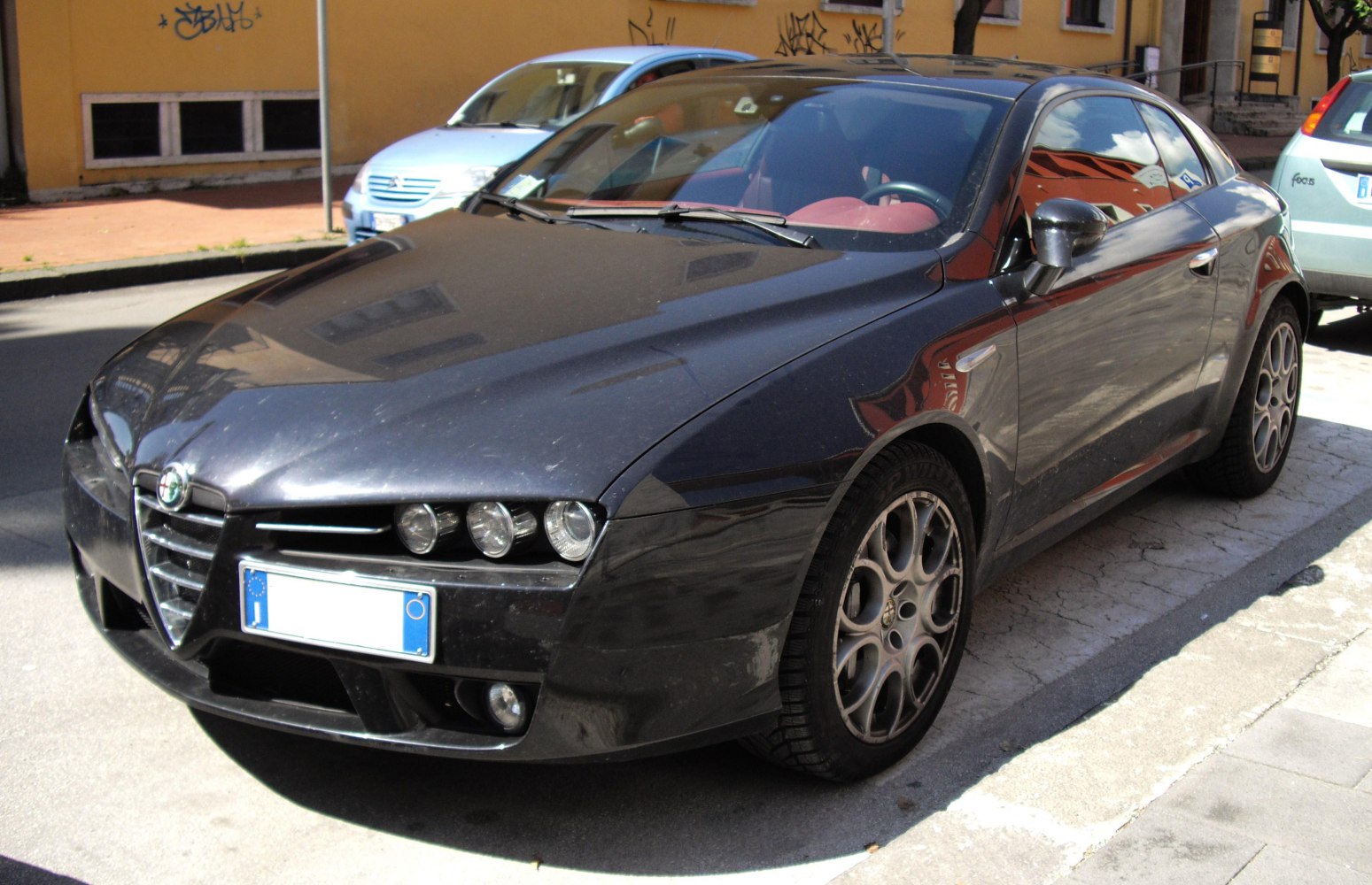 Triple headlights and alloy wheels on a sleek coupe front view