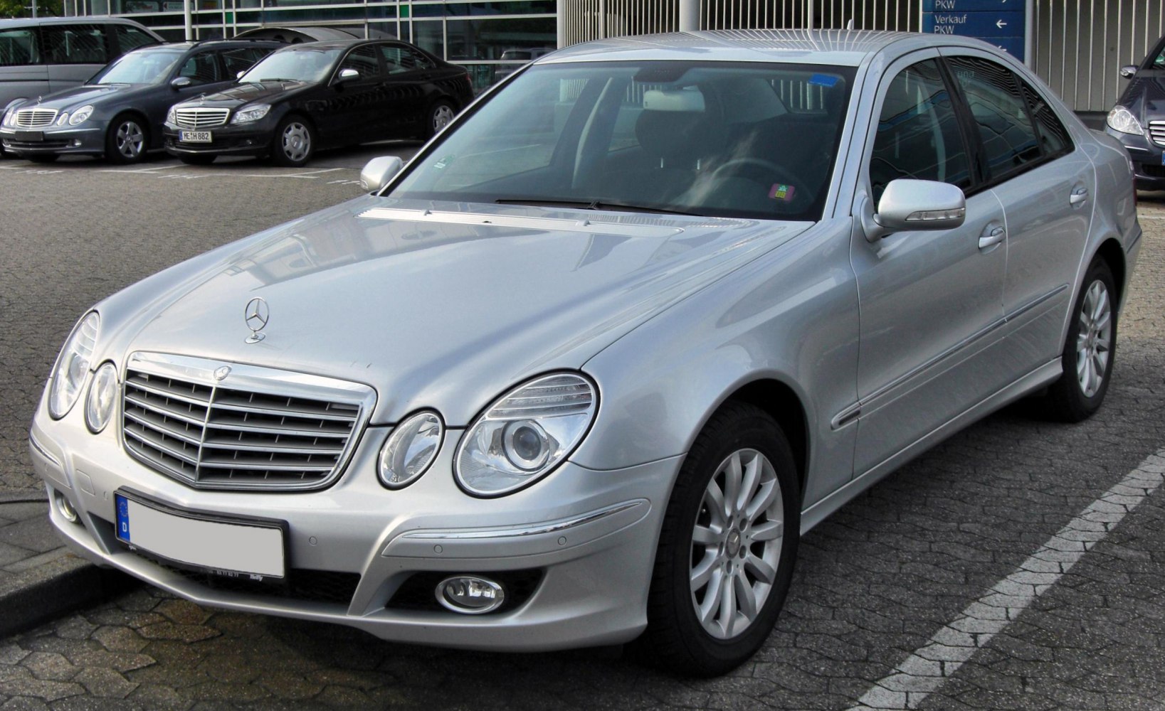 Front three-quarter view of silver sedan with four round headlights and prominent grille.