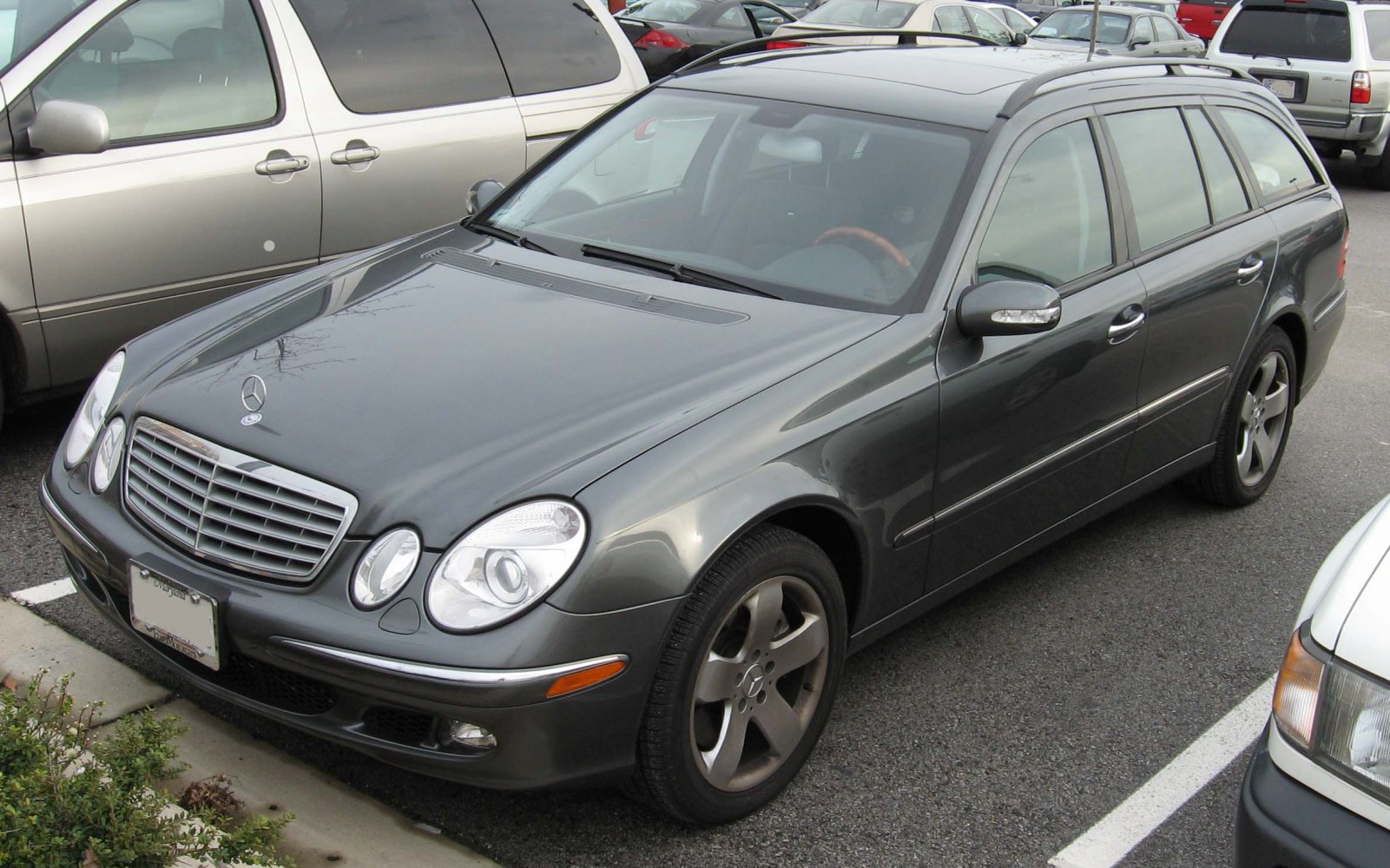 Front-side view of a dark estate vehicle with distinctive oval headlights and five-spoke alloy wheels