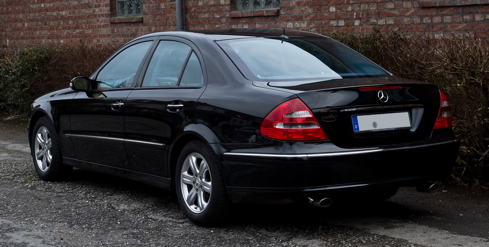 Rear side view of black sedan with tail lights and exhaust pipe