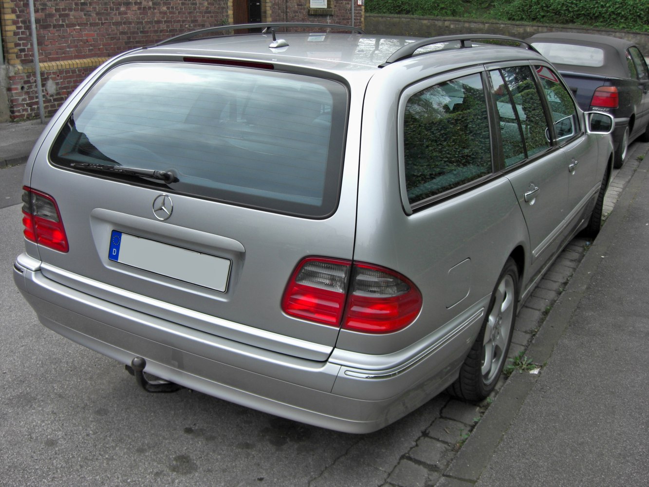 Rear view of a facelift Mercedes E-class station wagon with roof rails and taillights