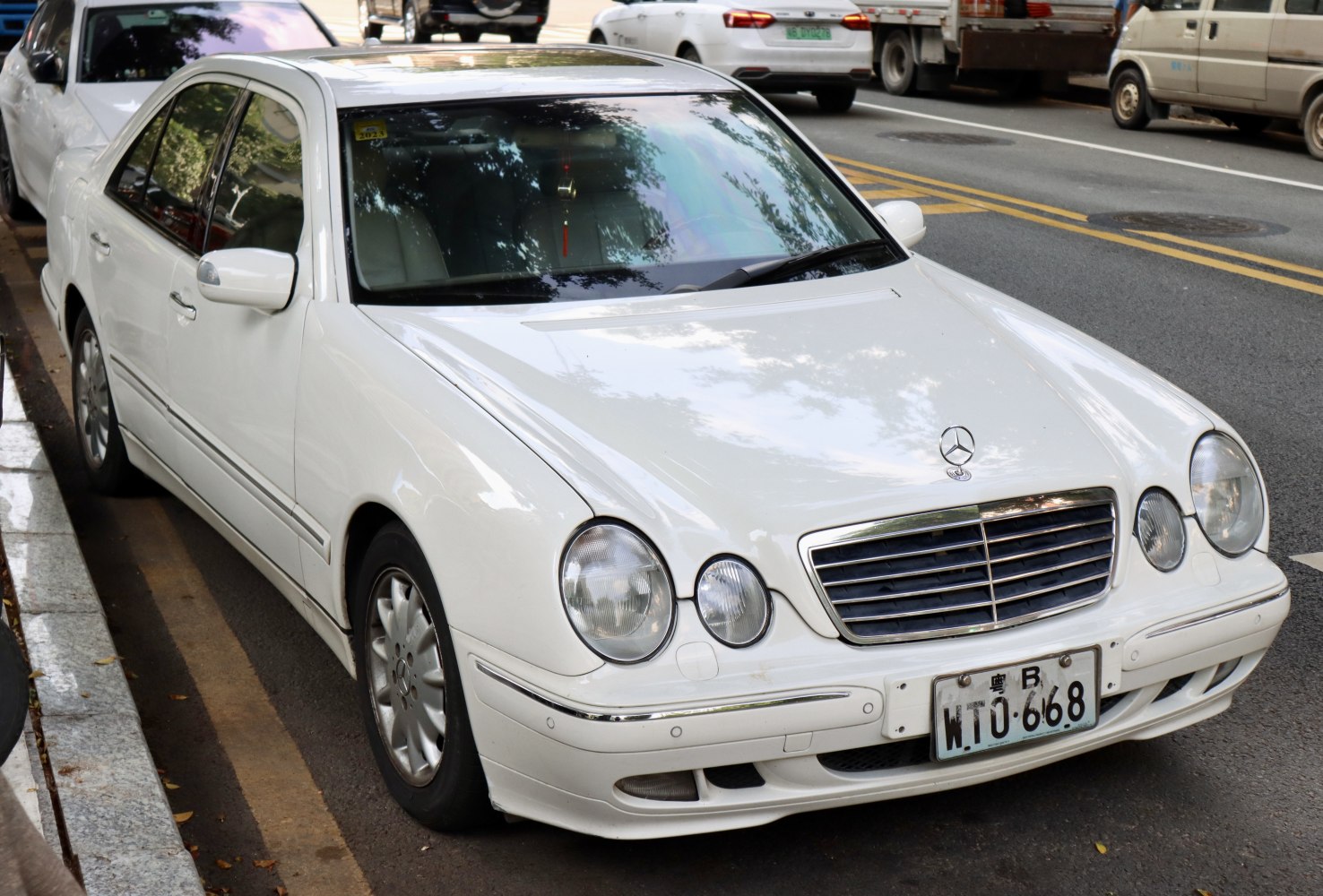 Twin round headlights and chrome grille on a white luxury sedan