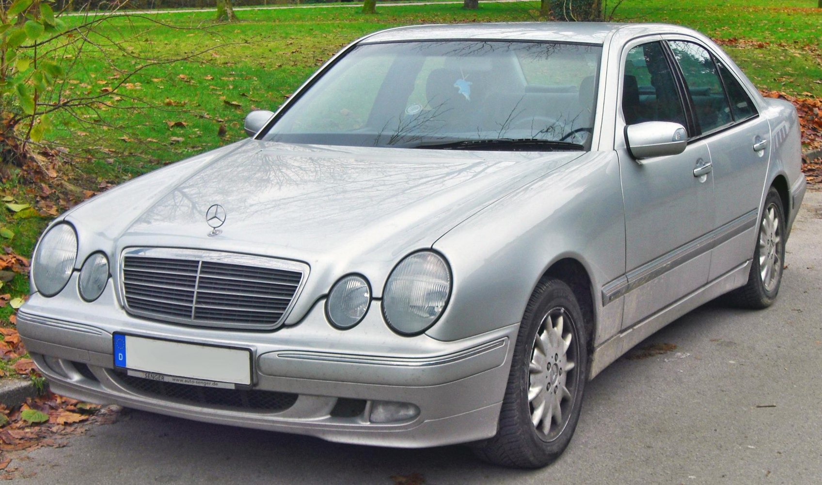 Front grille and dual round headlights of a silver sedan