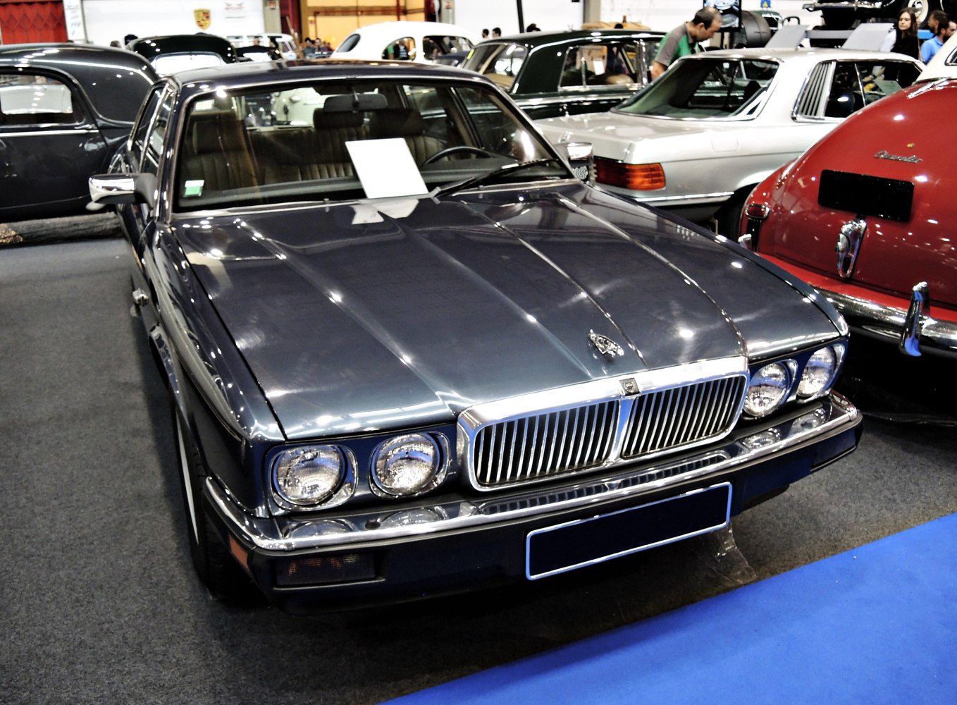 Quad round headlights and chrome grille on classic luxury sedan front.