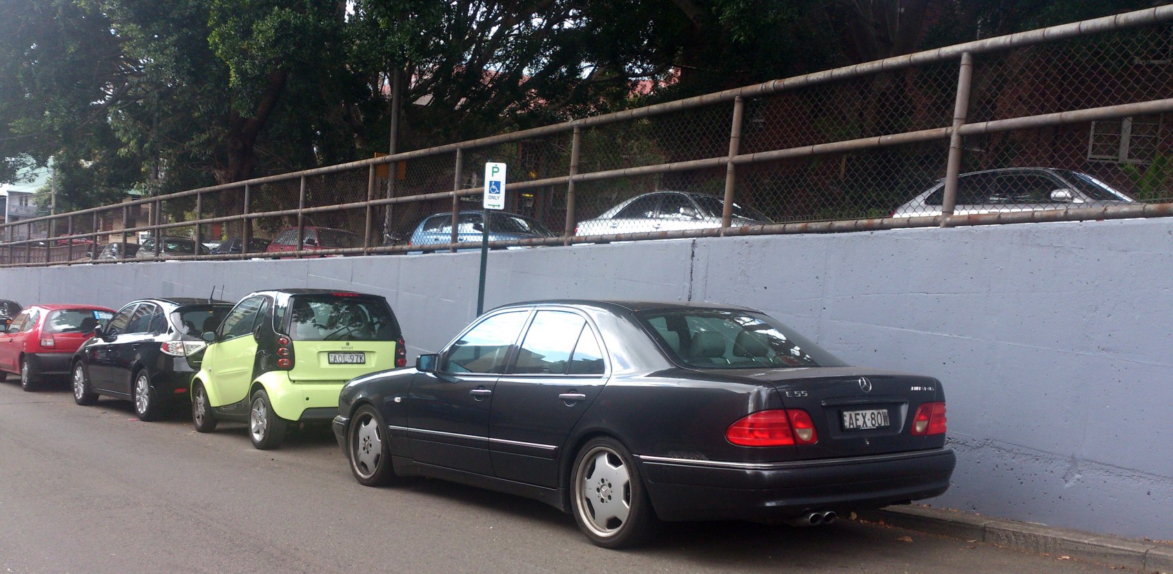 Black sedan with notable tail lights and alloy wheels parked on the street