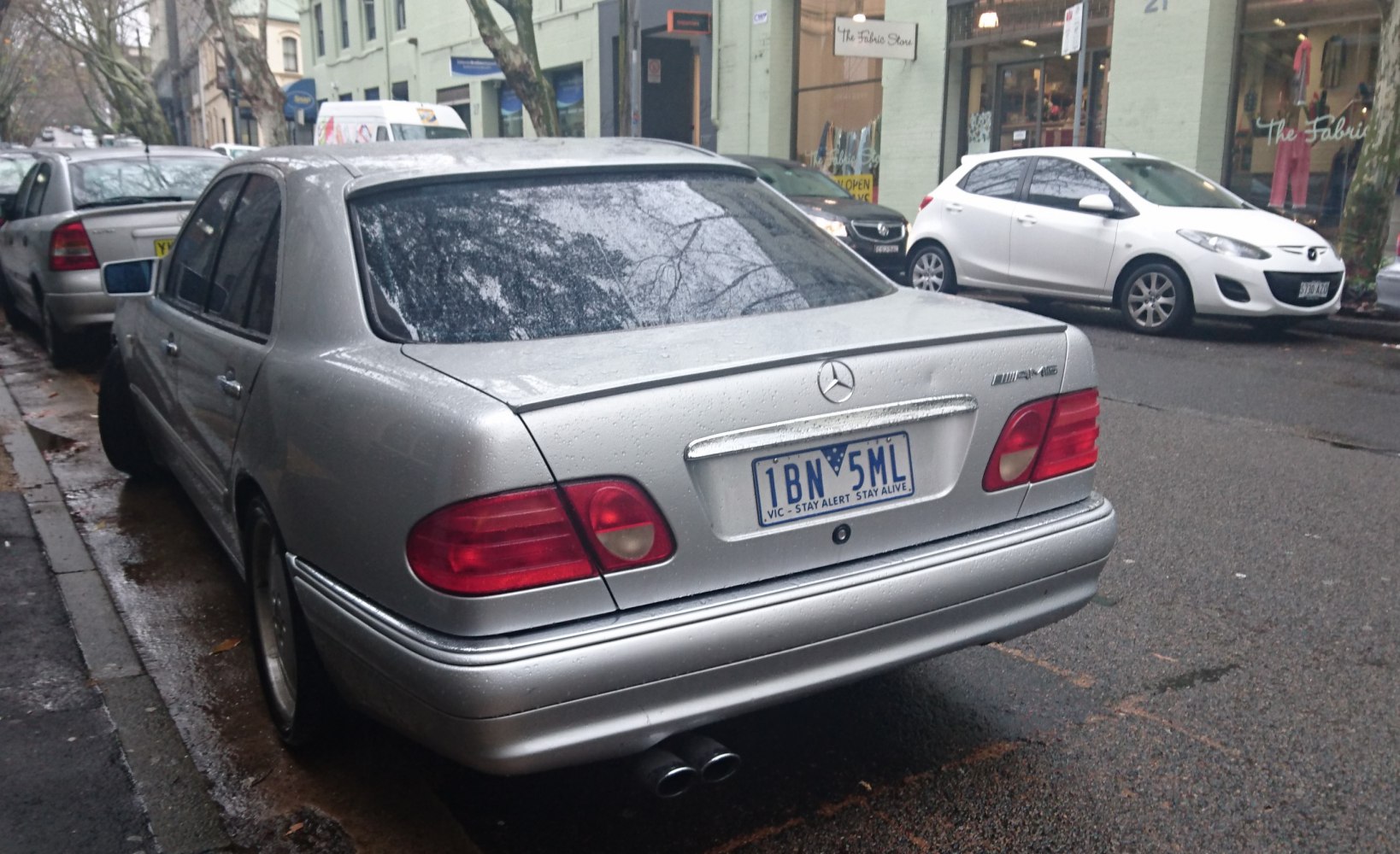 Rear view of silver sedan with distinctive taillights and dual exhaust