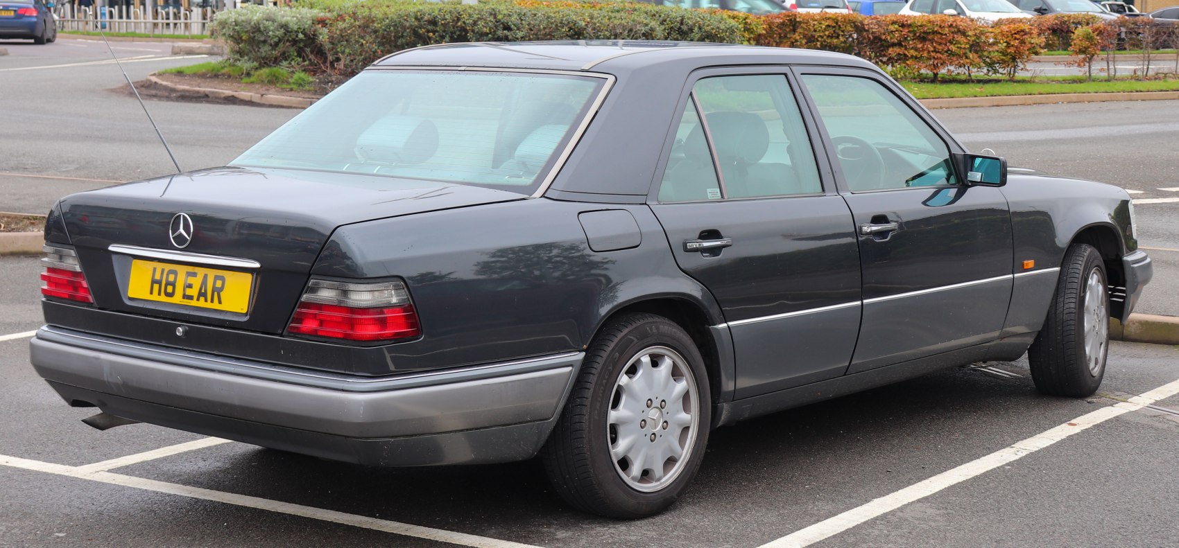 Rear view of 1990s sedan with classic taillights and alloy wheels.