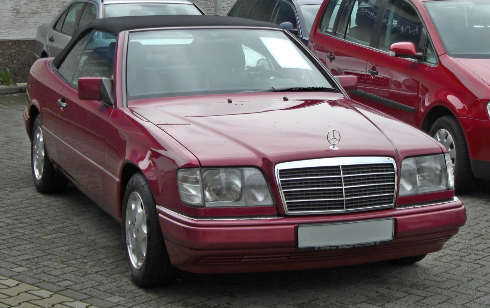 Red convertible with black soft top and prominent front grille