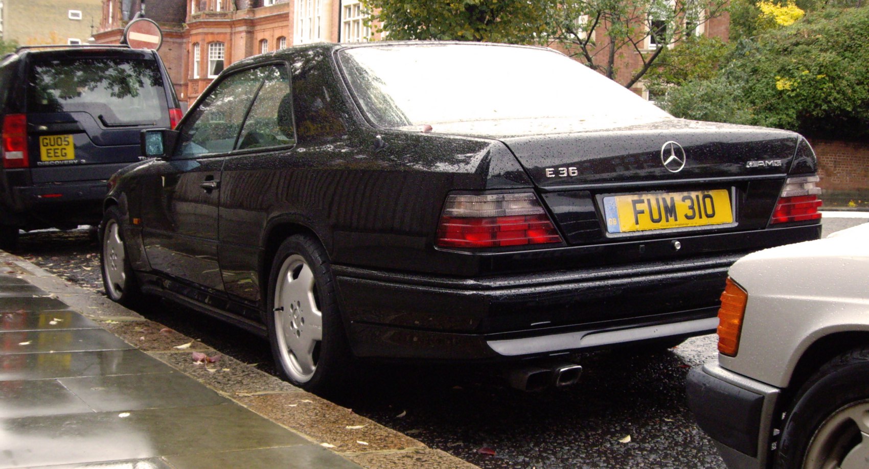 Rear view of a coupe with AMG and E36 badges, tail lights and dual exhaust tips.