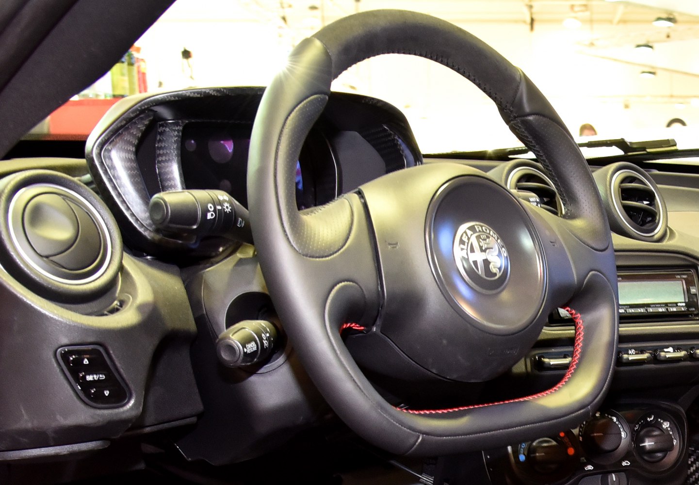Leather steering wheel with red stitching and dashboard controls