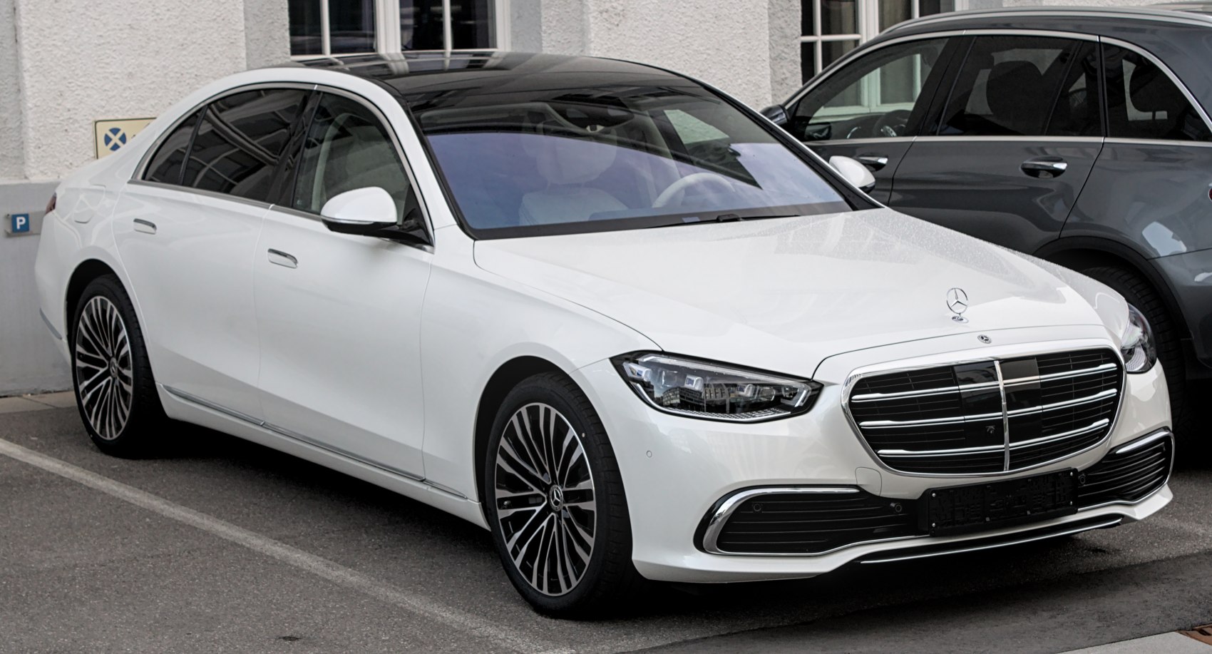 Luxury white sedan with chromed grille and multi-spoke wheels