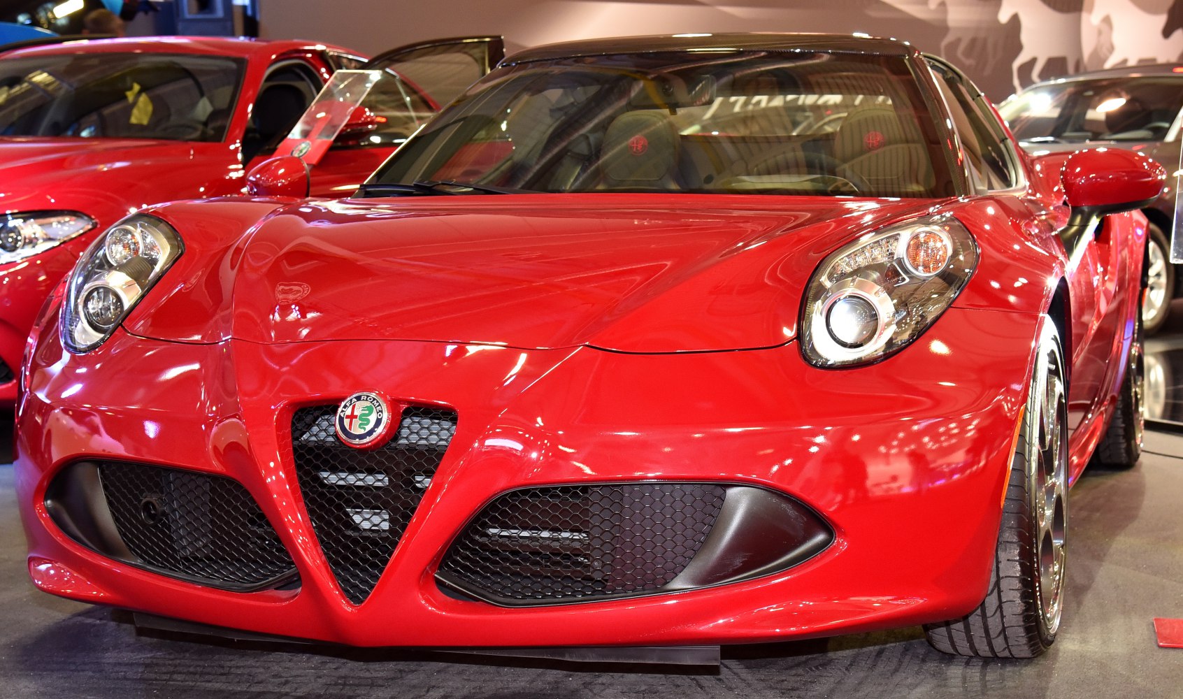 Sporty red coupe with distinctive V-shaped grille and round headlights.