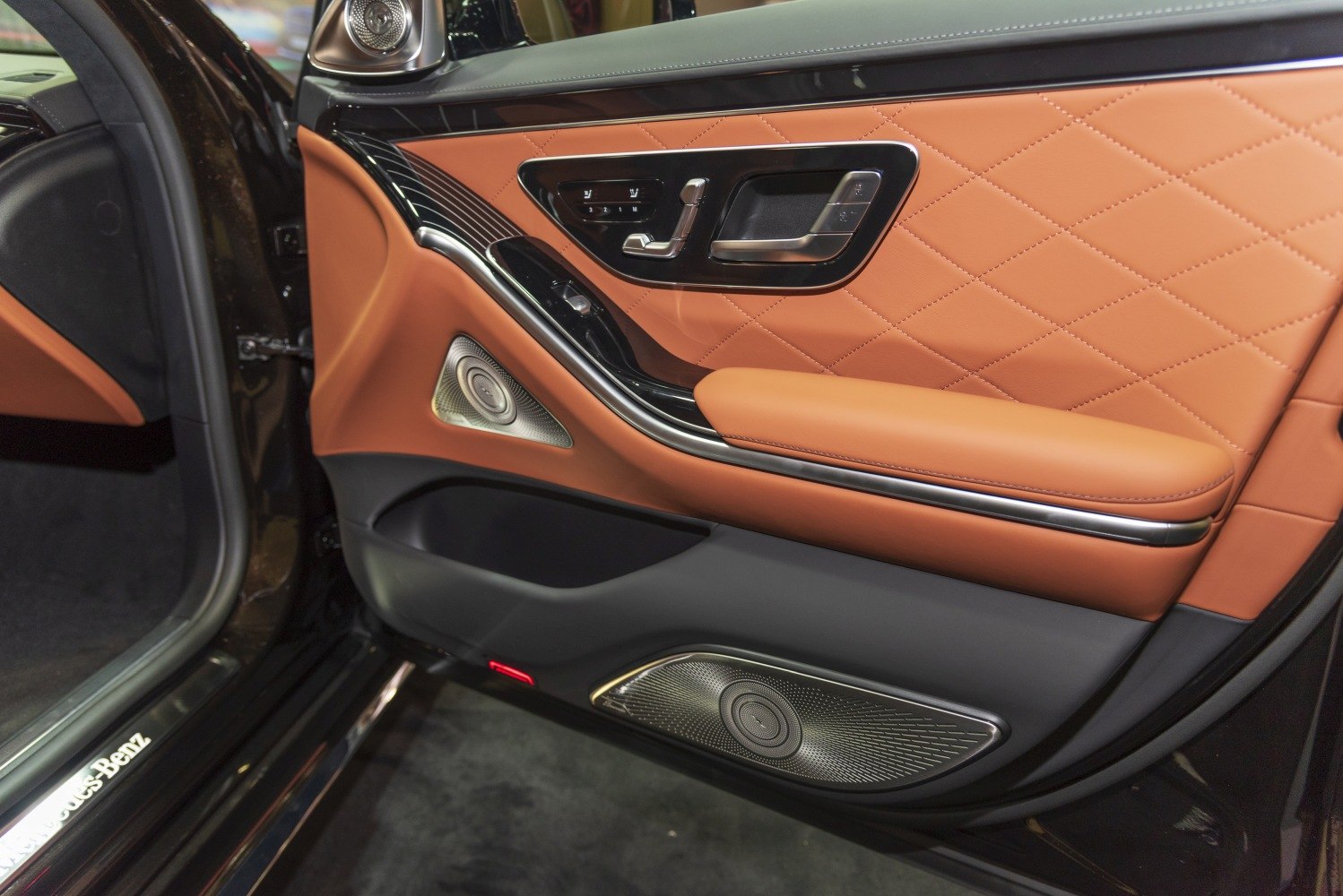 Luxury car door panel with leather upholstery, speaker system, and seat controls