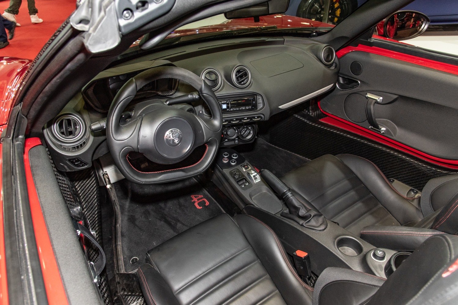 Leather seats and sporty steering wheel with carbon fiber trim in convertible car interior.