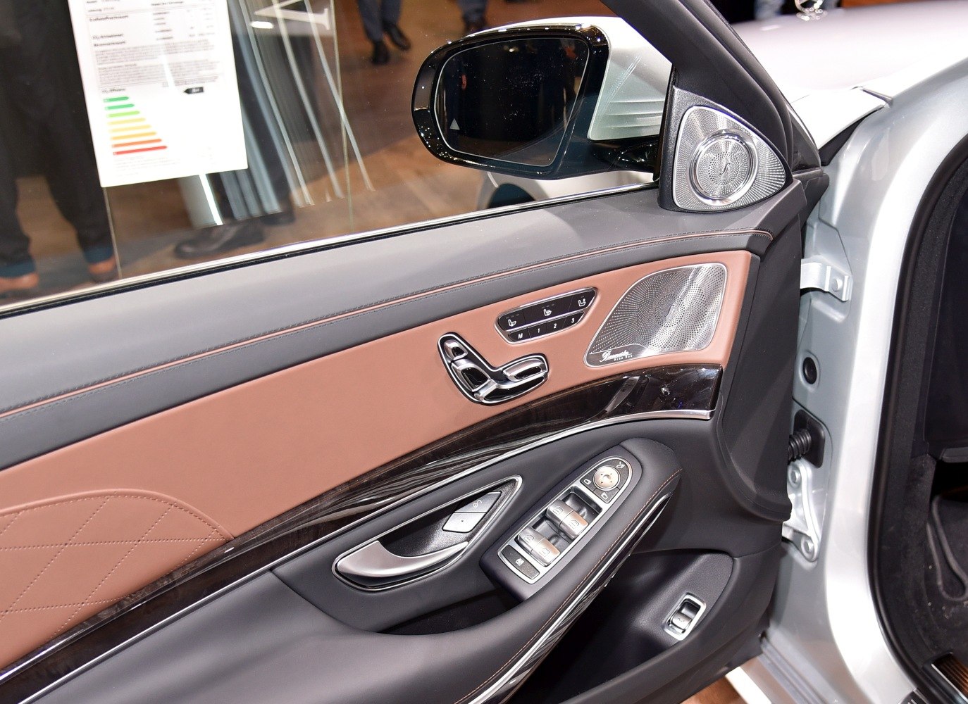 Luxury car door with wood trim, speaker grille, seat controls, and window switches.