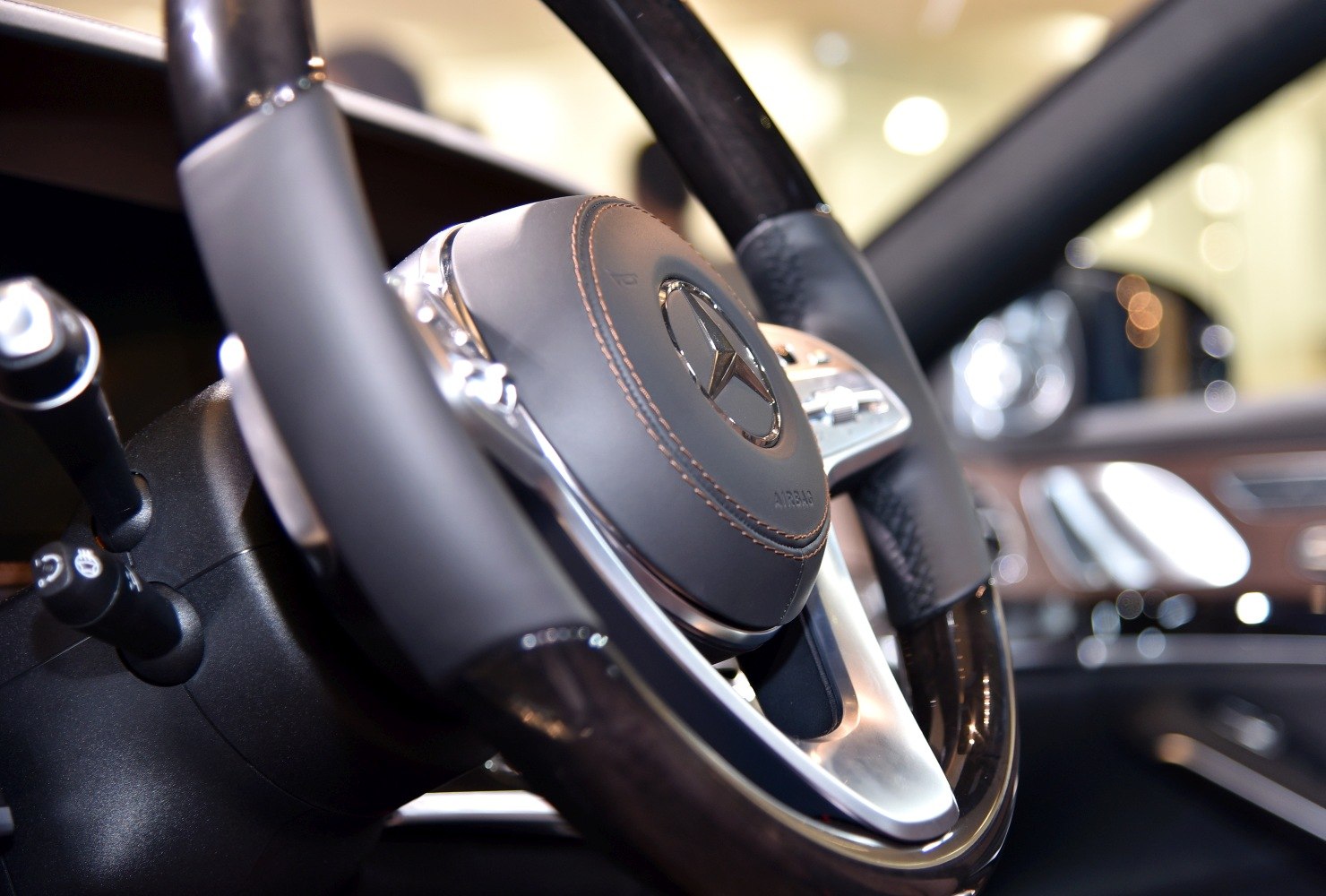 Close-up of luxury steering wheel with control buttons and leather stitching