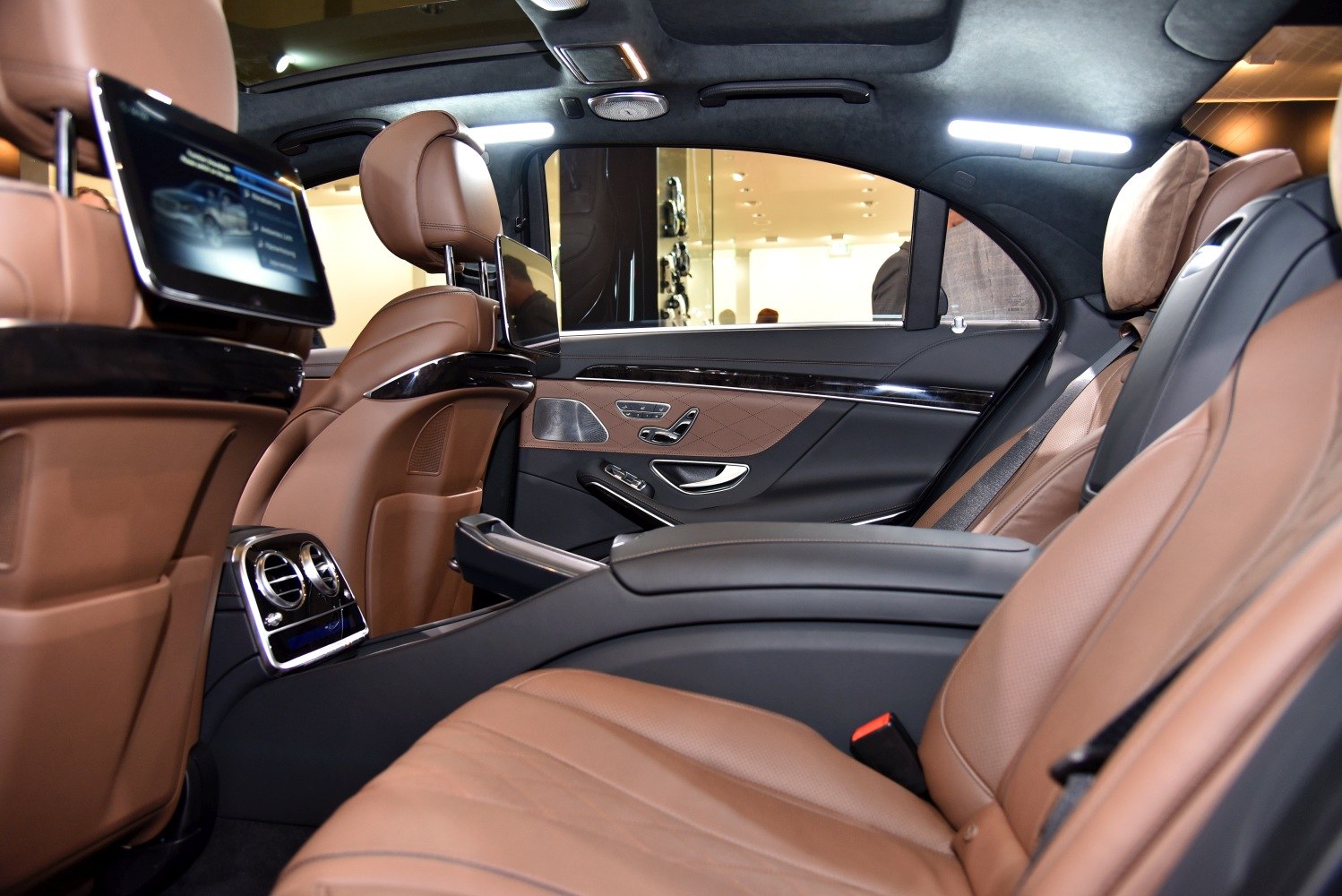 Rear luxury seats with brown leather and dual touchscreen entertainment displays
