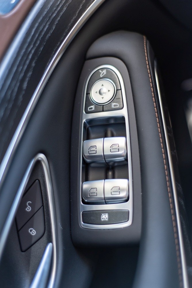 Power window and mirror controls panel on interior door trim with stitched leather