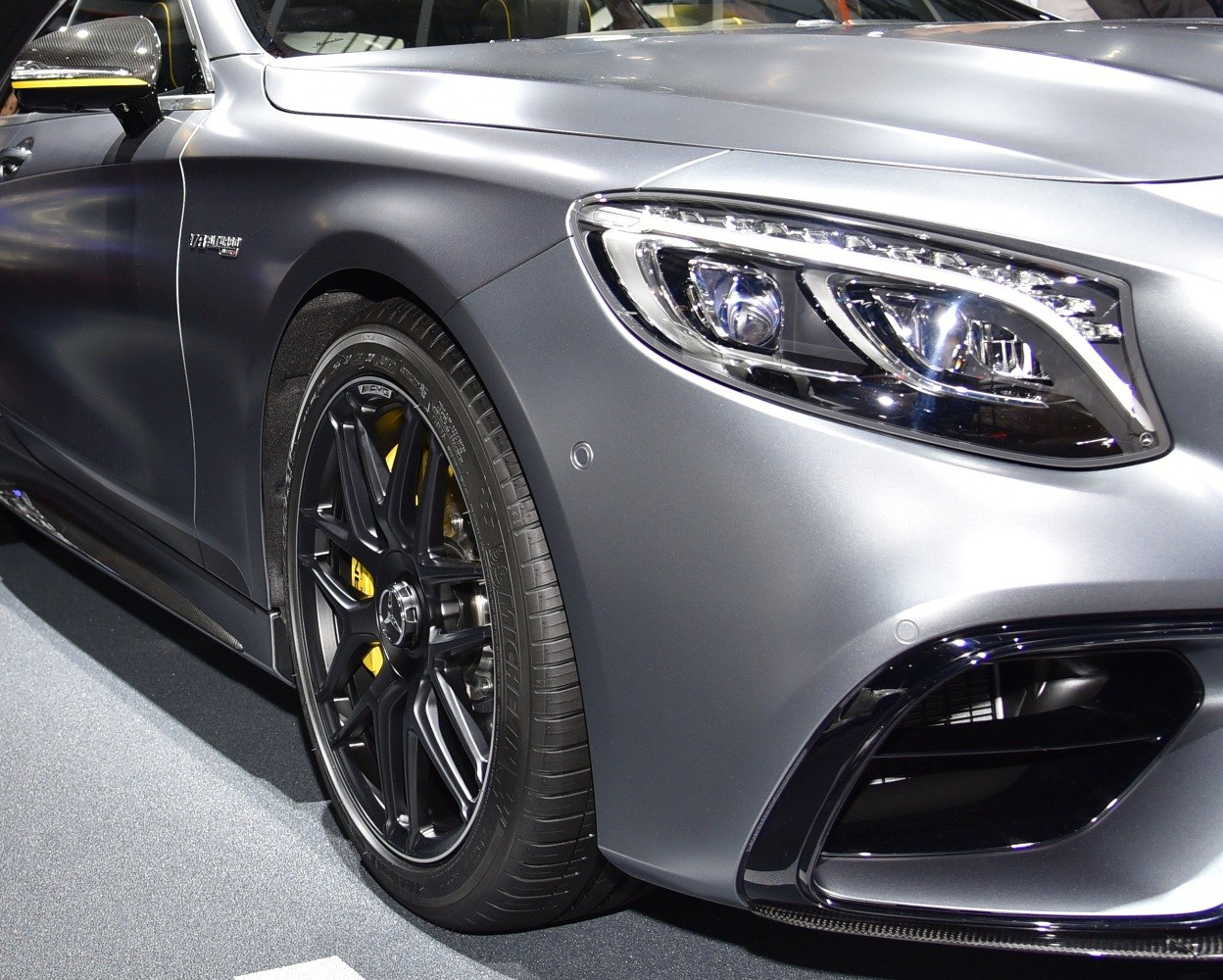 Close-up front headlight and black alloy wheel with yellow brake caliper