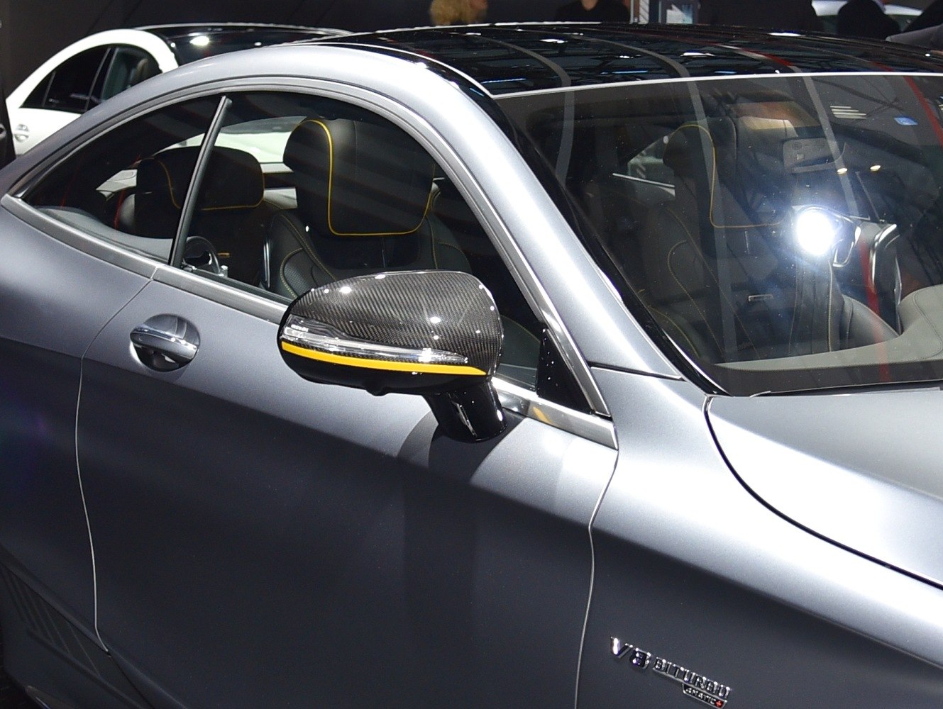 Carbon fiber side mirror with yellow accent and detailed black leather interior.