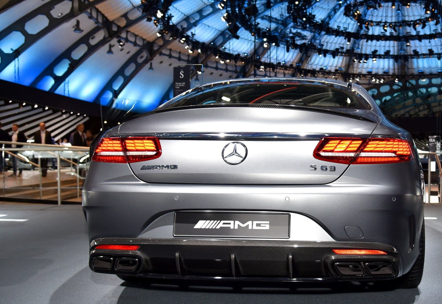 Rear view of luxury coupe with illuminated tail lights and quad exhausts