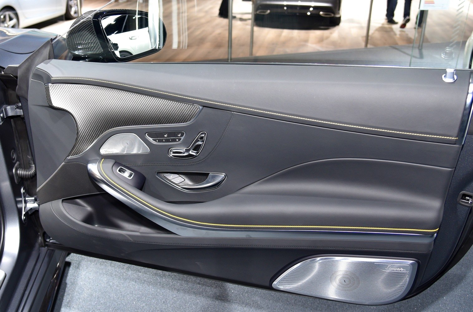 Luxury car door panel with carbon fiber, leather, advanced seat controls, and premium speaker