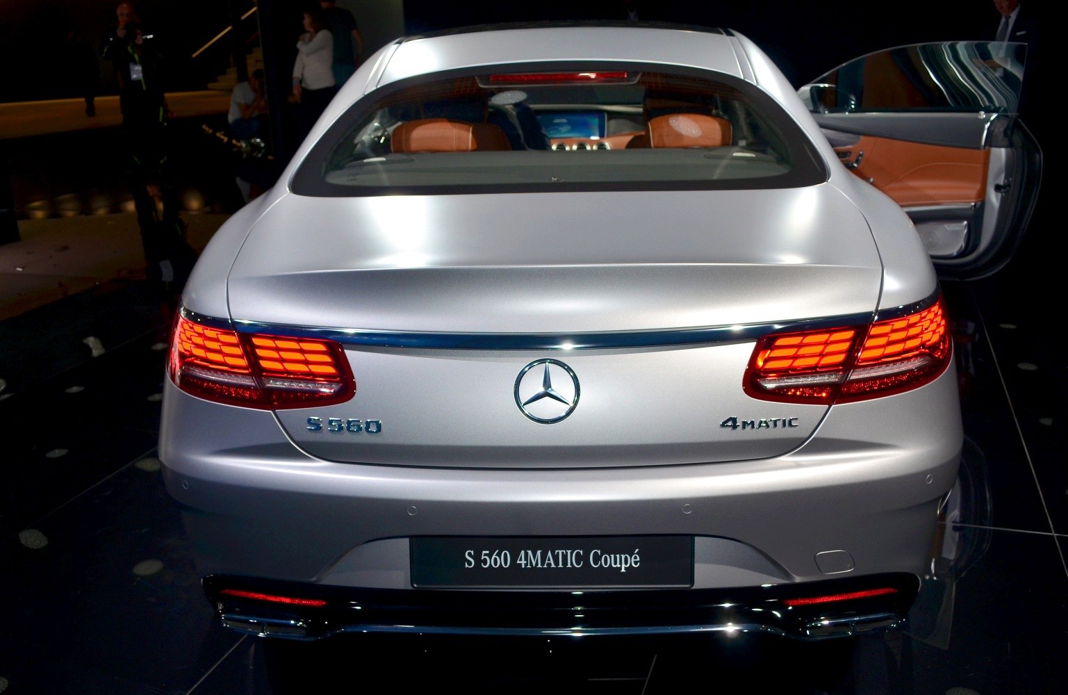 Rear view of luxury coupe with illuminated taillights and badges